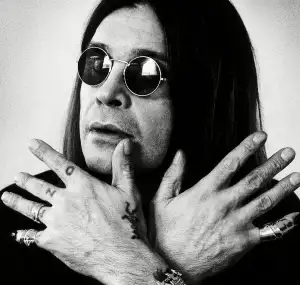 Ozzy Osbourne showing his rings and hand tattoos