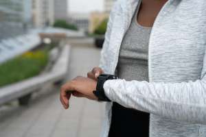 Person walking outdoors wearing a fitness tracker to count their daily steps.