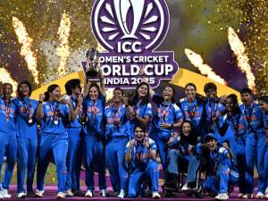 India women's cricket team celebrates with the World Cup trophy as gold confetti falls.